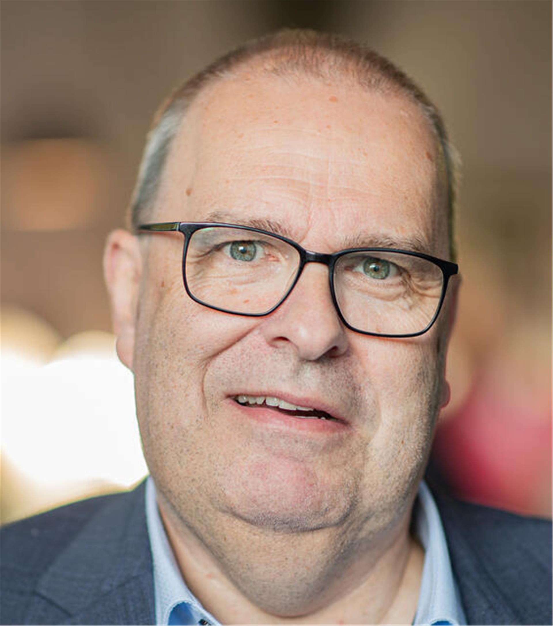 Ein Mann mit Brille und sehr kurzen Haaren.