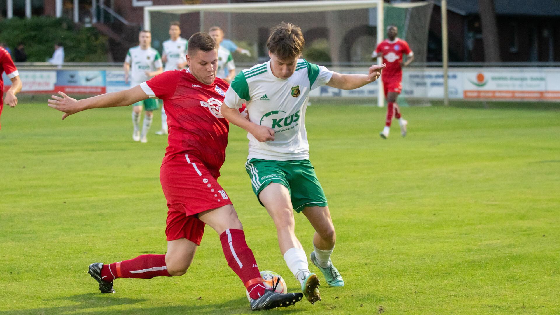 Zwei Männer in Sporttrikots kämpfen um einen Ball.