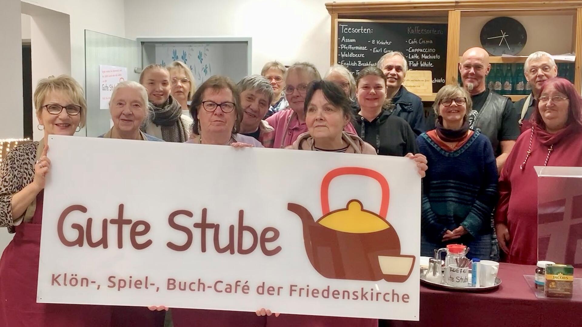 Das Team der Guten Stube hält ein Schild hoch. 