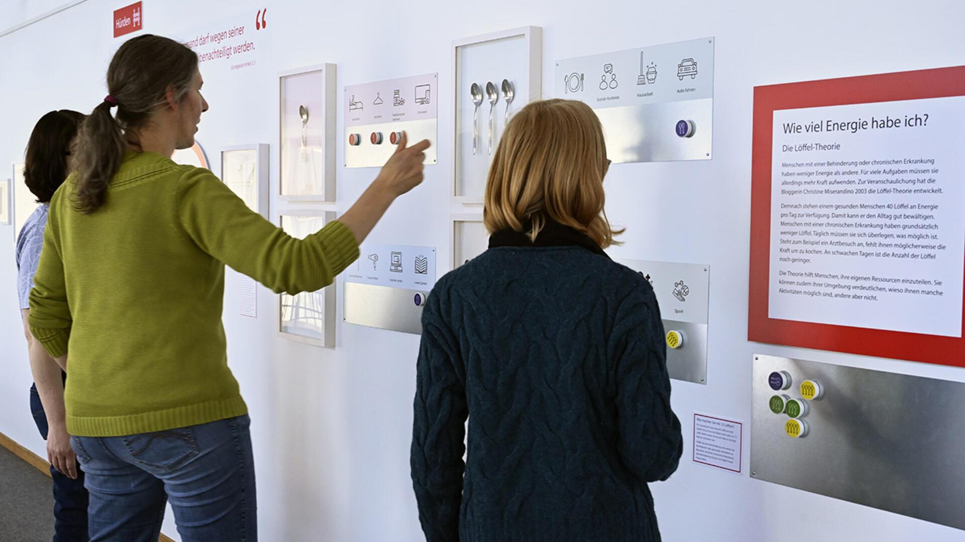 Drei Personen vor einer Ausstellungswand.
