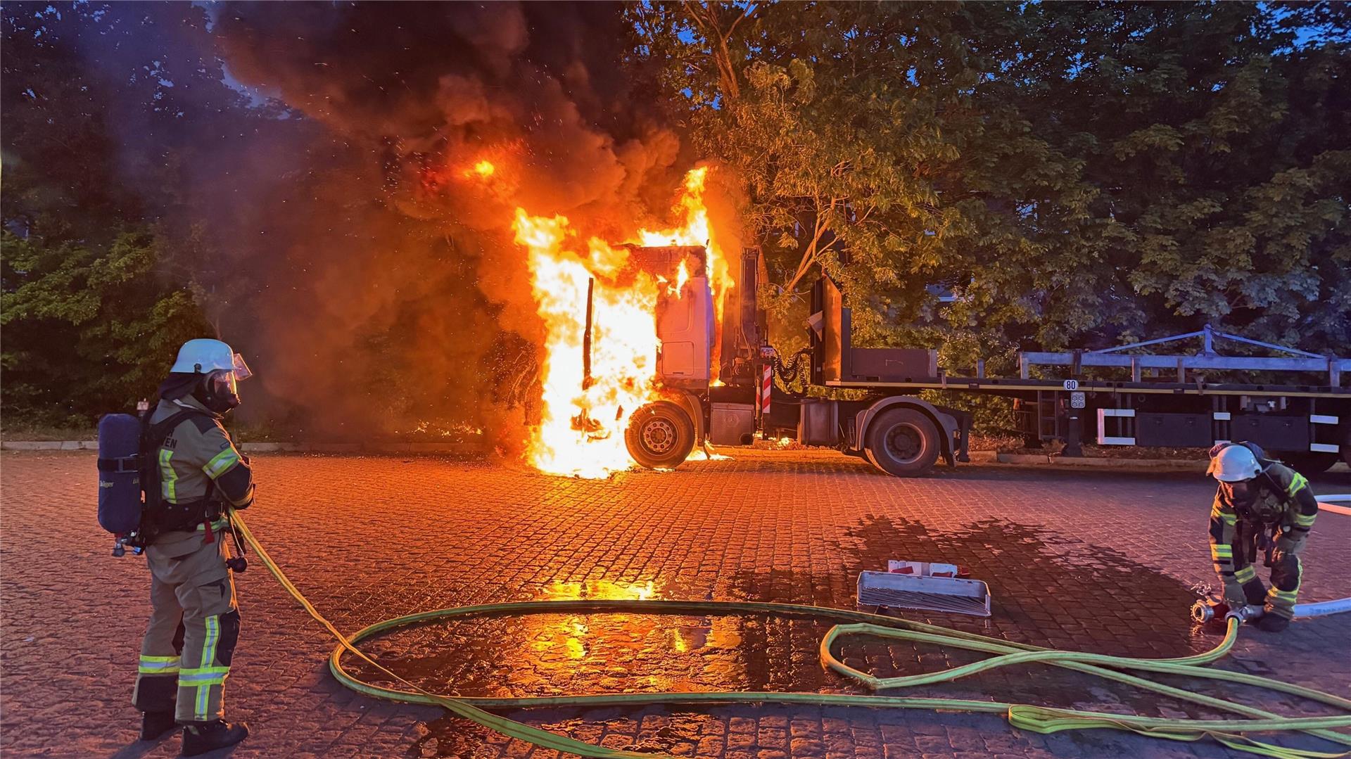 Feuerwehrleute löschen einen brennenden Lkw.