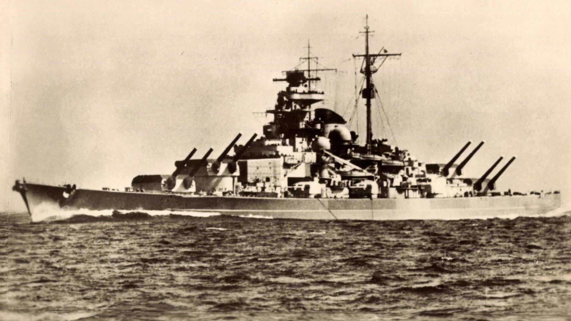 Auf einer Schwarz-Weiß-Fotografie ist ein großes Kriegsschiff zu sehen.