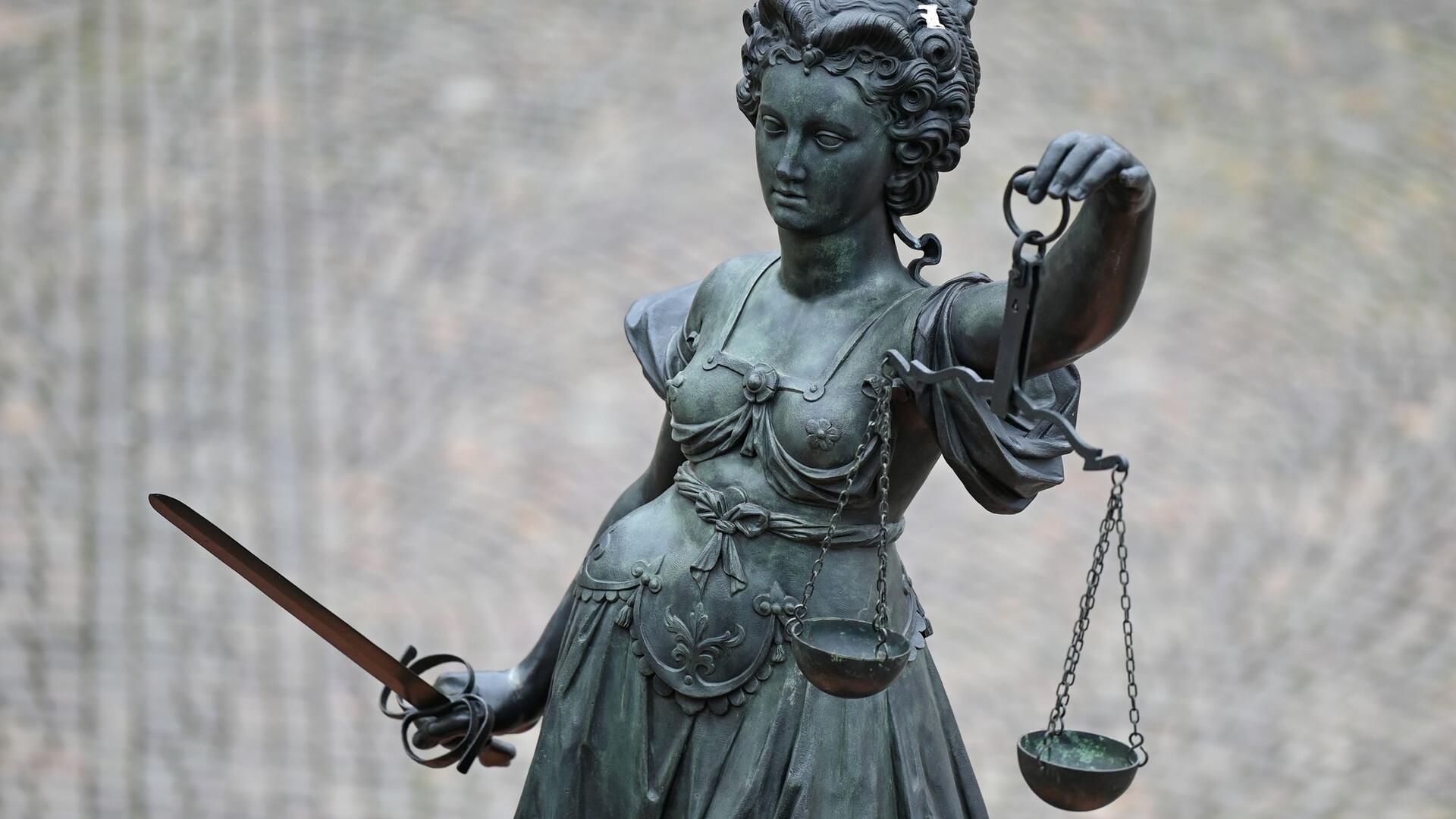 Eine Statue der Justitia hält eine Waage und ein Schwert in der Hand.