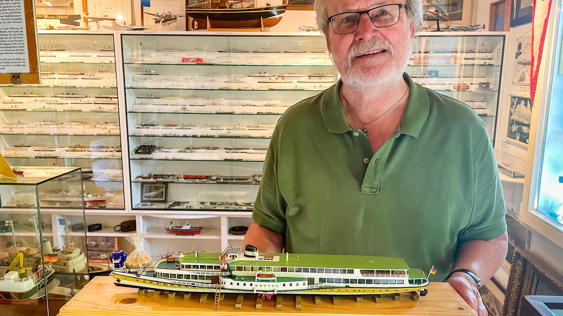 Ein Mann hält ein Modellschiff  in den Händen