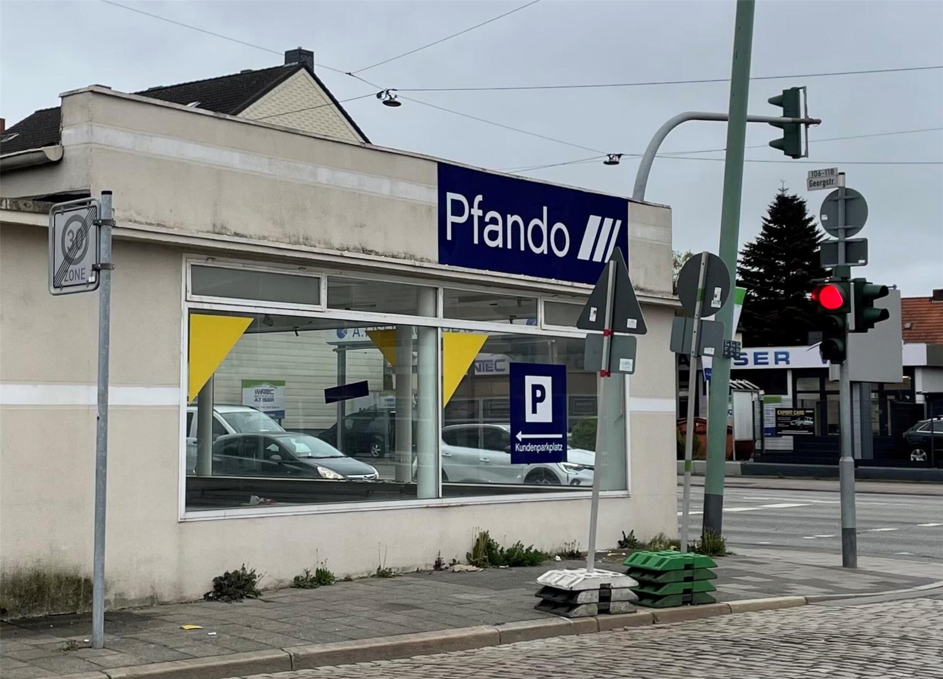 Ein Haus mit der Aufschrift "Pfando". Daneben eine Ampel, deren Rotlicht leuchtet.