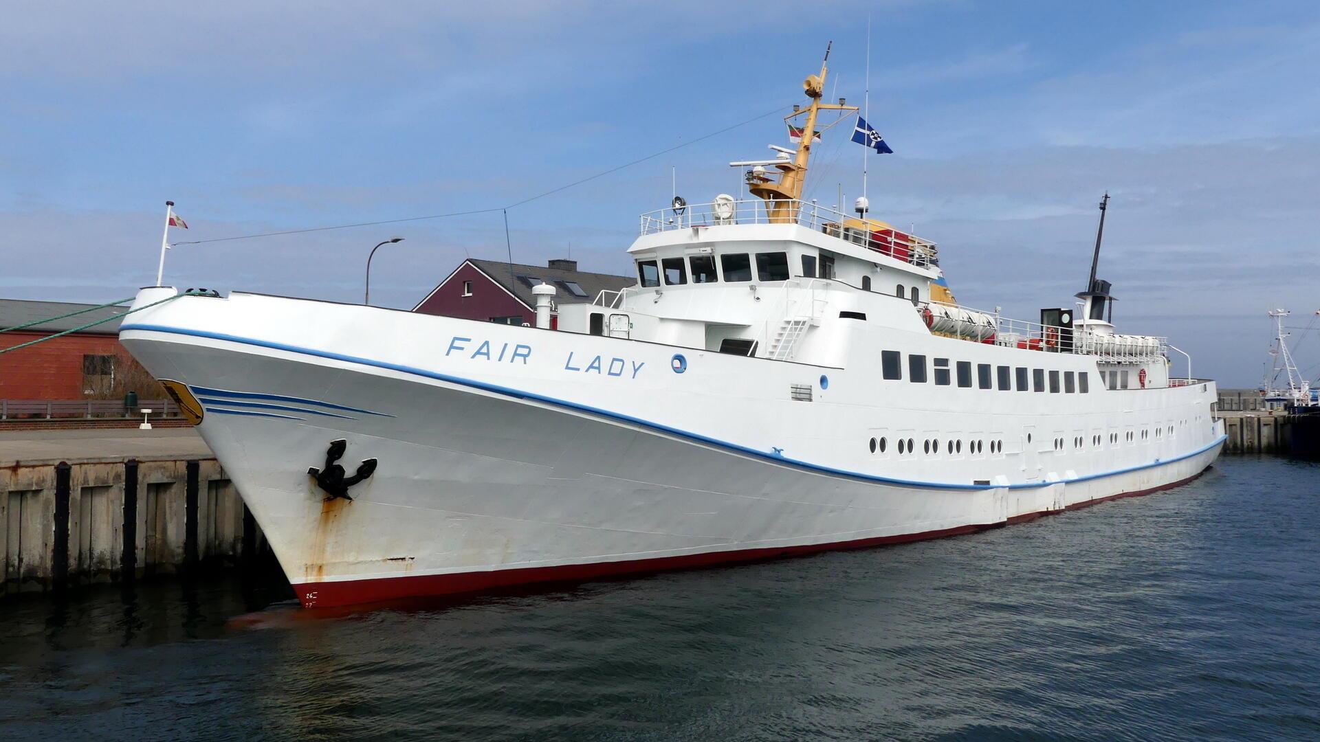Ein weißes Schiff liegt an einer Kaje.