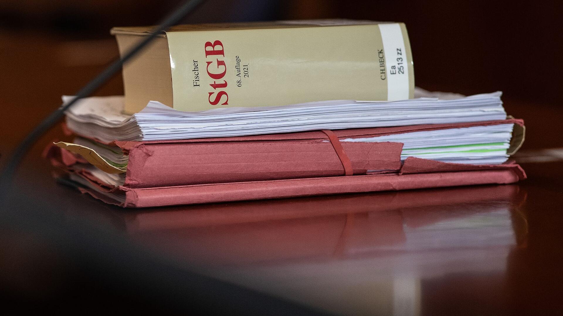Sexueller Missbrauch in Kita: Bewährungsstrafe für Erzieher Das Strafgesetzbuch und Akten liegen in einem Gericht auf dem Tisch.
