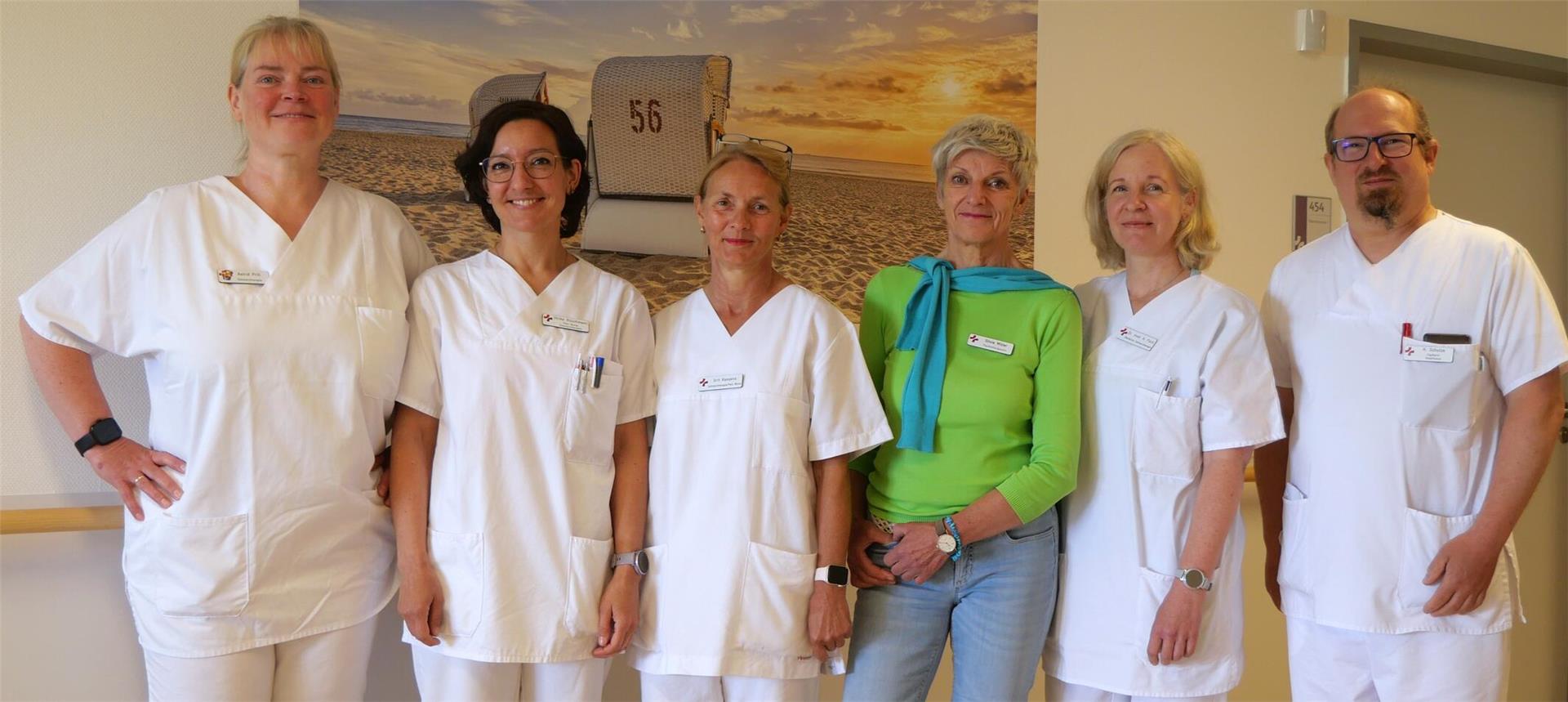 Sechs Mitarbeiter eines Krankenhauses stellen sich zum Gruppenfoto auf. Alle sind in weißer Kleidung zu sehen, bis auf die dritte Person von rechts - die trägt ein grünes Oberteil und eine Jeans. Das Team der Schmerztherapie am Klinikum Bremerhaven-Reinkenheide (KBR) bietet nun stationäre Behandlung auf der neuen Station 2A – mit multiprofessioneller Unterstützung und ganzheitlichem Ansatz.