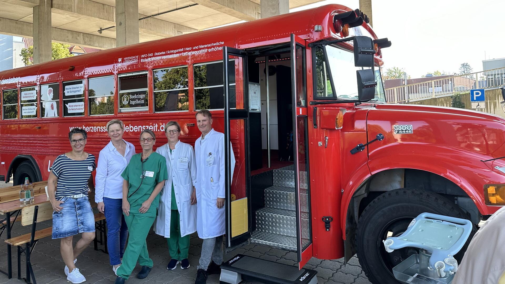 Ärzte in weißen Kitteln vor einem roten Fahrzeug: Das Team des Agaplesion Diakonieklinikums Rotenburg freut sich auf viele  Besucher: Der rote Info-Bus „Herzenssache Lebenszeit“ macht am 10. September in Rotenburg Halt. Fachärzte informieren kostenlos über Schlaganfall, Herz-Kreislauf-Erkrankungen und Diabetes. 