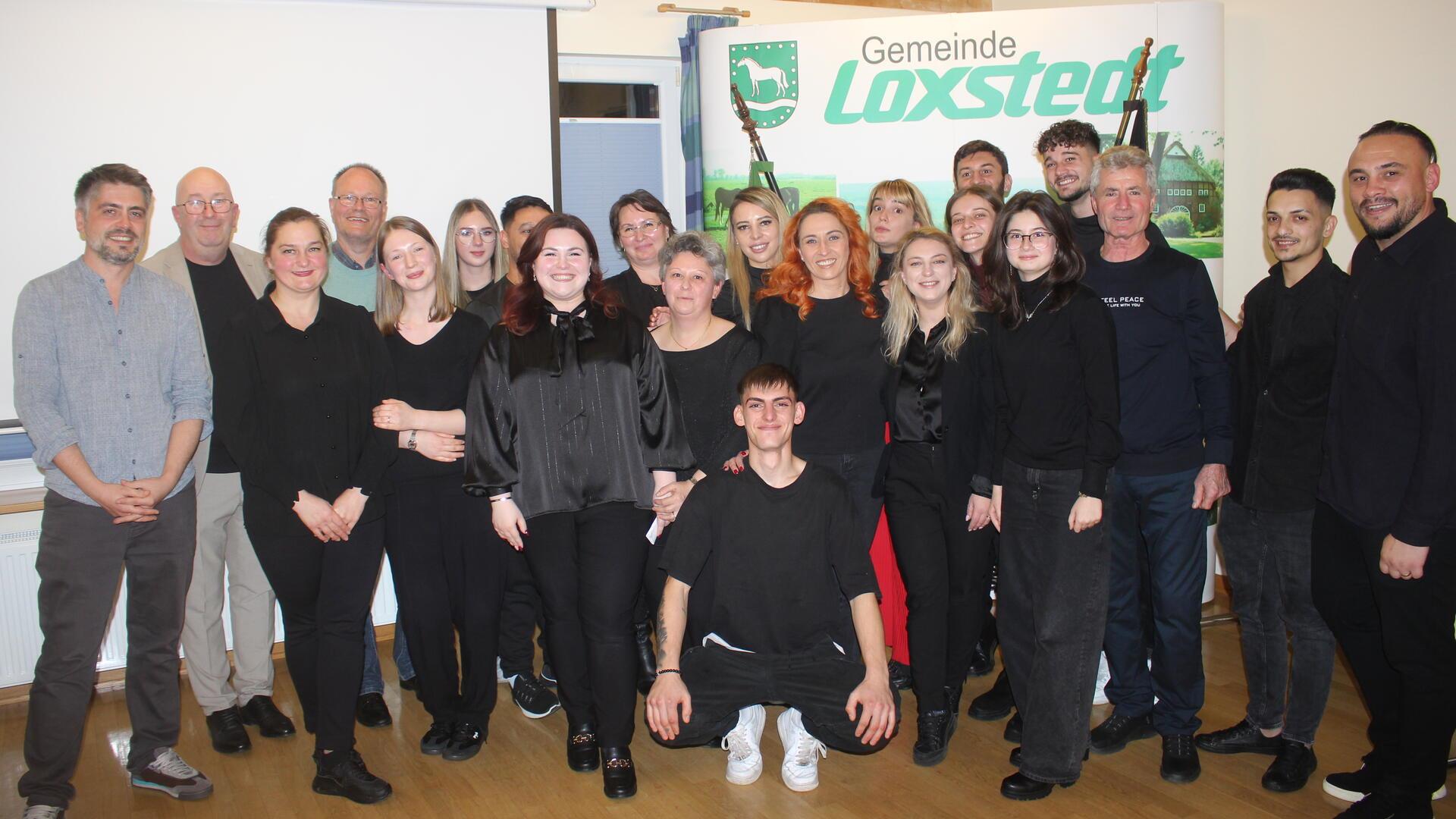 Eine Gruppe von Menschen, die vor dem Schild "Gemeinde Loxstedt" steht.