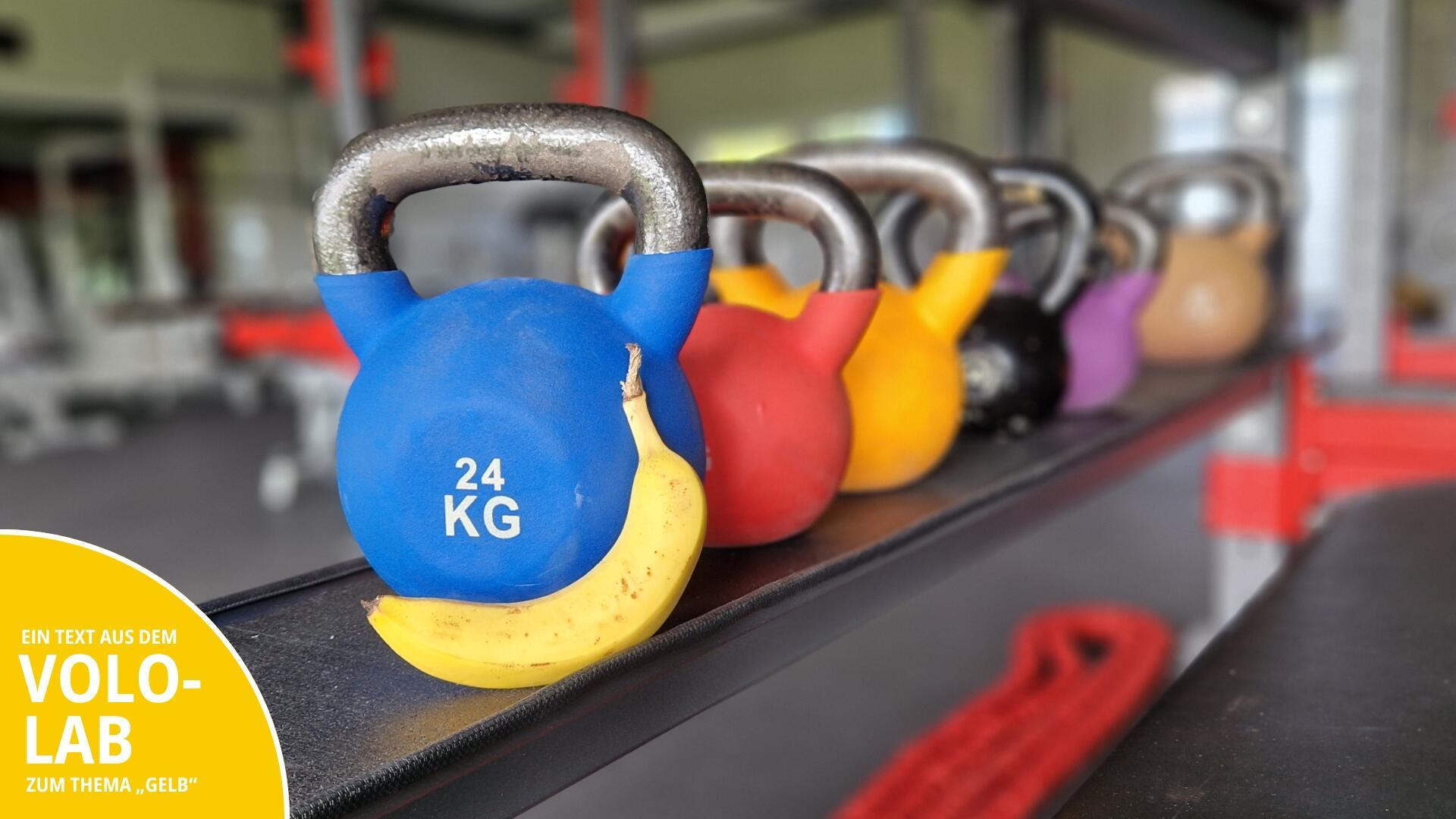 Eine Banane vor bunten Kettlebells.