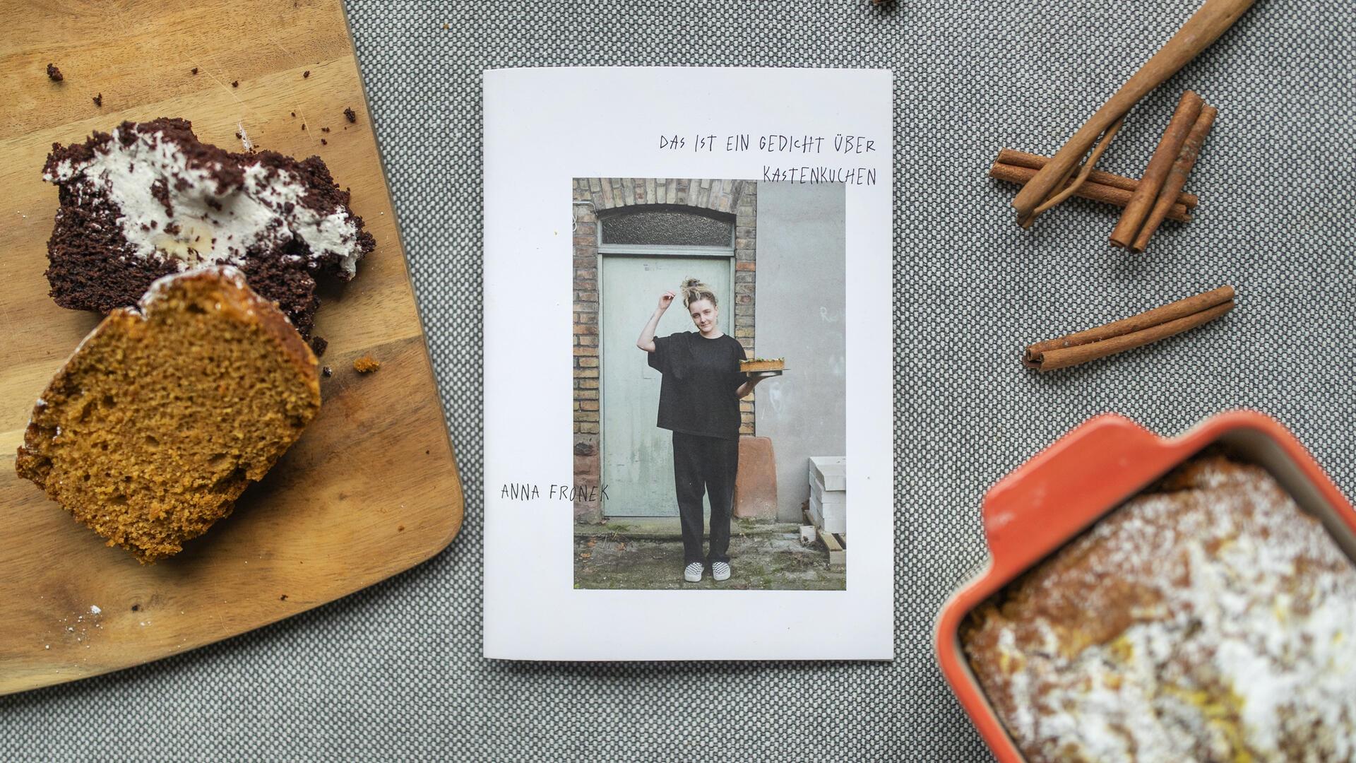 Das Backbuch "Das ist ein Gedicht über Kastenkuchen" zwischen zwei Kastenkuchen und Zimtstangen-Deko. 