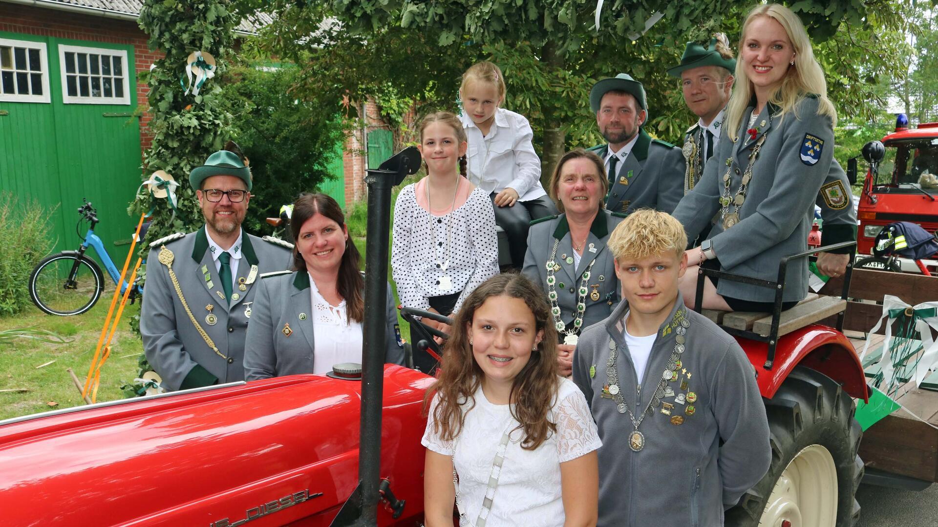 Männer, Frauen und Kinder haben sich an einem alten Trecker zum Foto aufgestellt