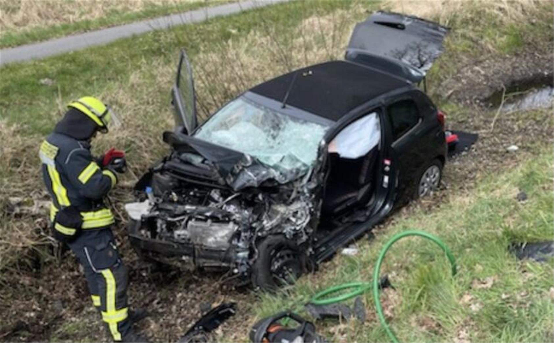 Ein zerstörtes Auto liegt auf einem Grünstreifen