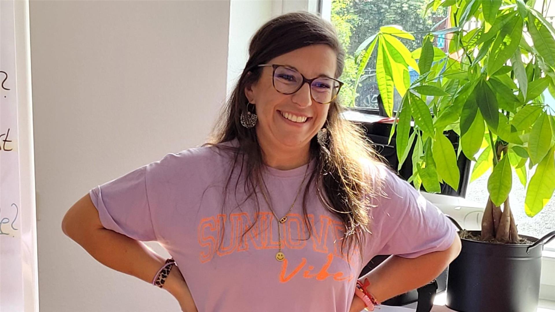 Eine lachende Frau mit Brille und dunklen langen Haaren.