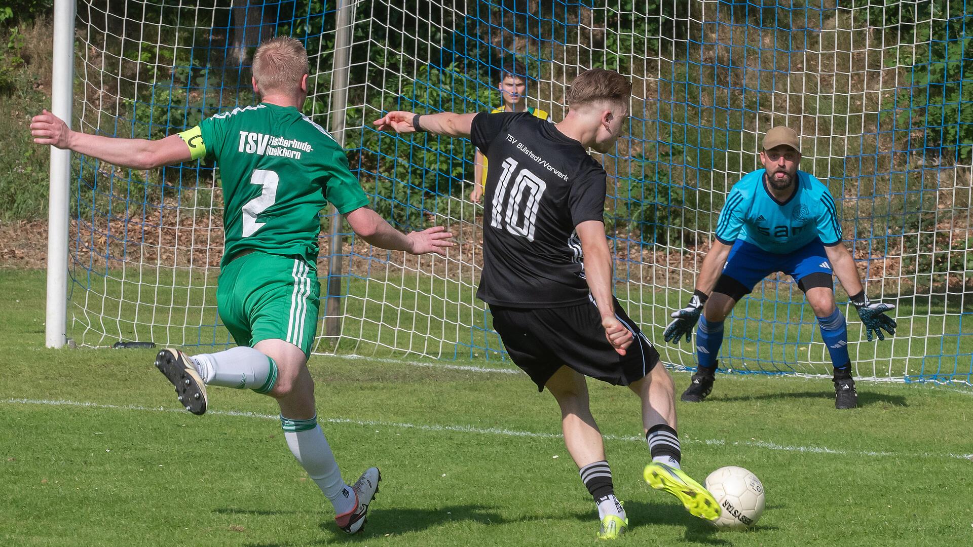 Ein Mann schießt einen Ball in Richtung eines Mannes, der vor einem Netz steht.
