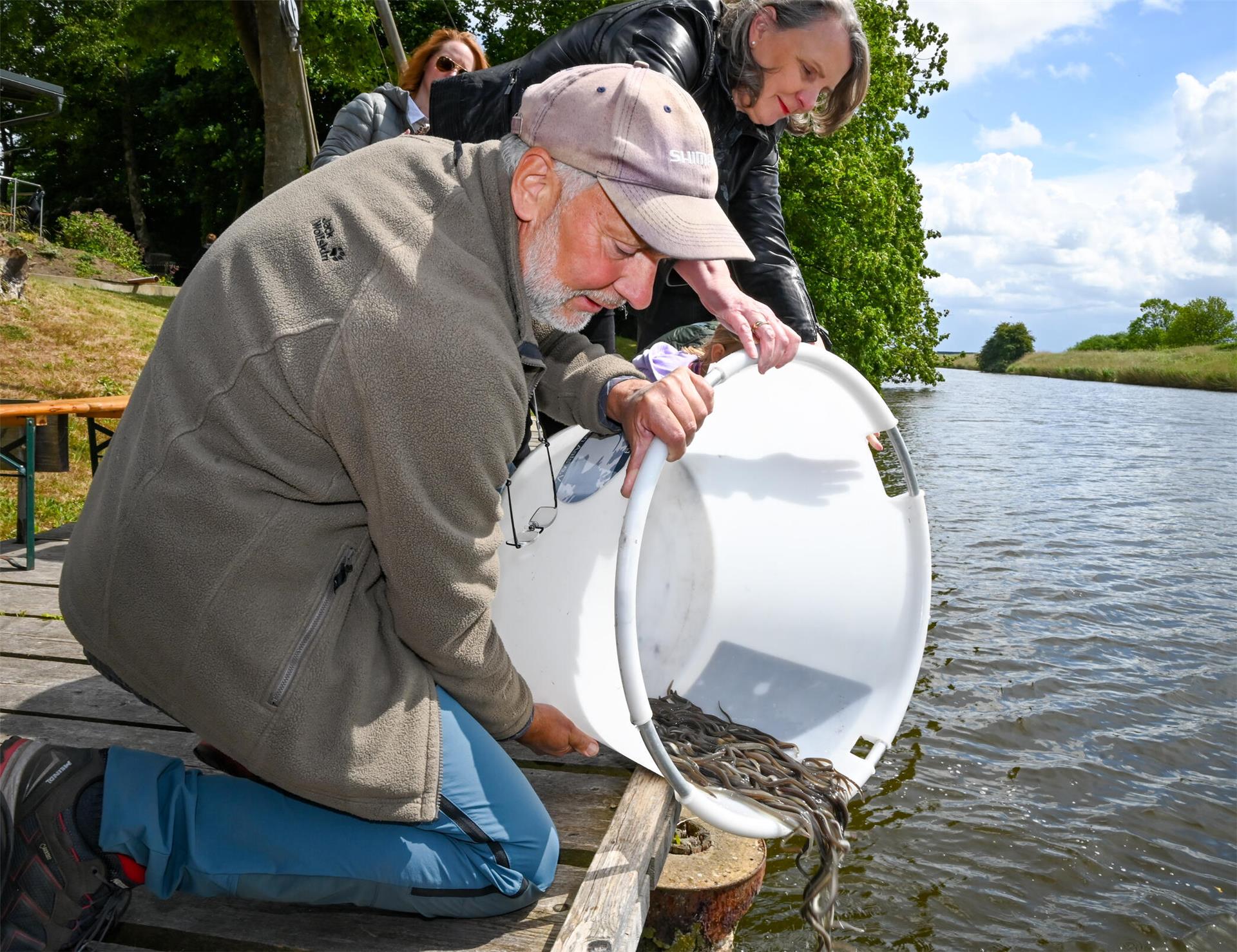 Aale werden von einem Mann und einer Frau in einen Fluss ausgesetzt.