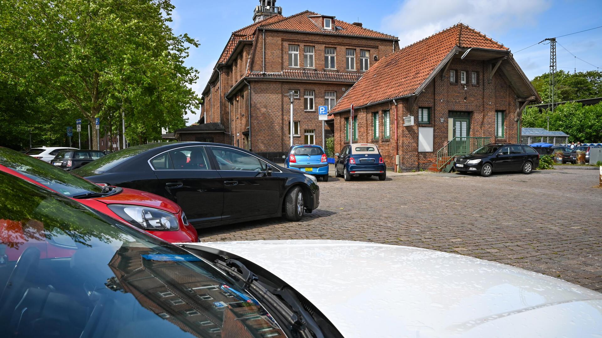 Parkende Autos vor dem Bahnhofsgebäude.