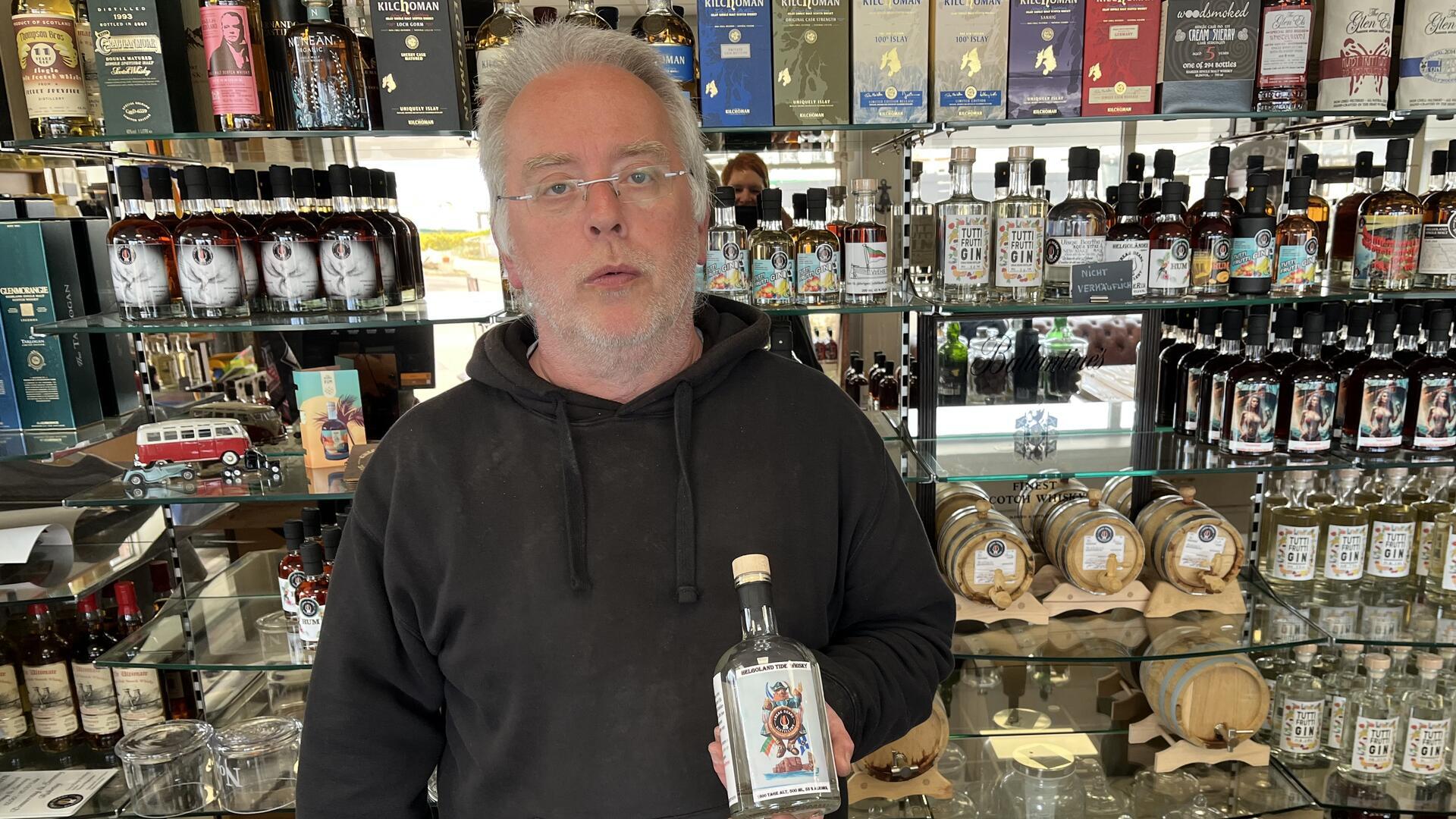 Ein Mann hält eine Flasche Schnaps in der Hand.