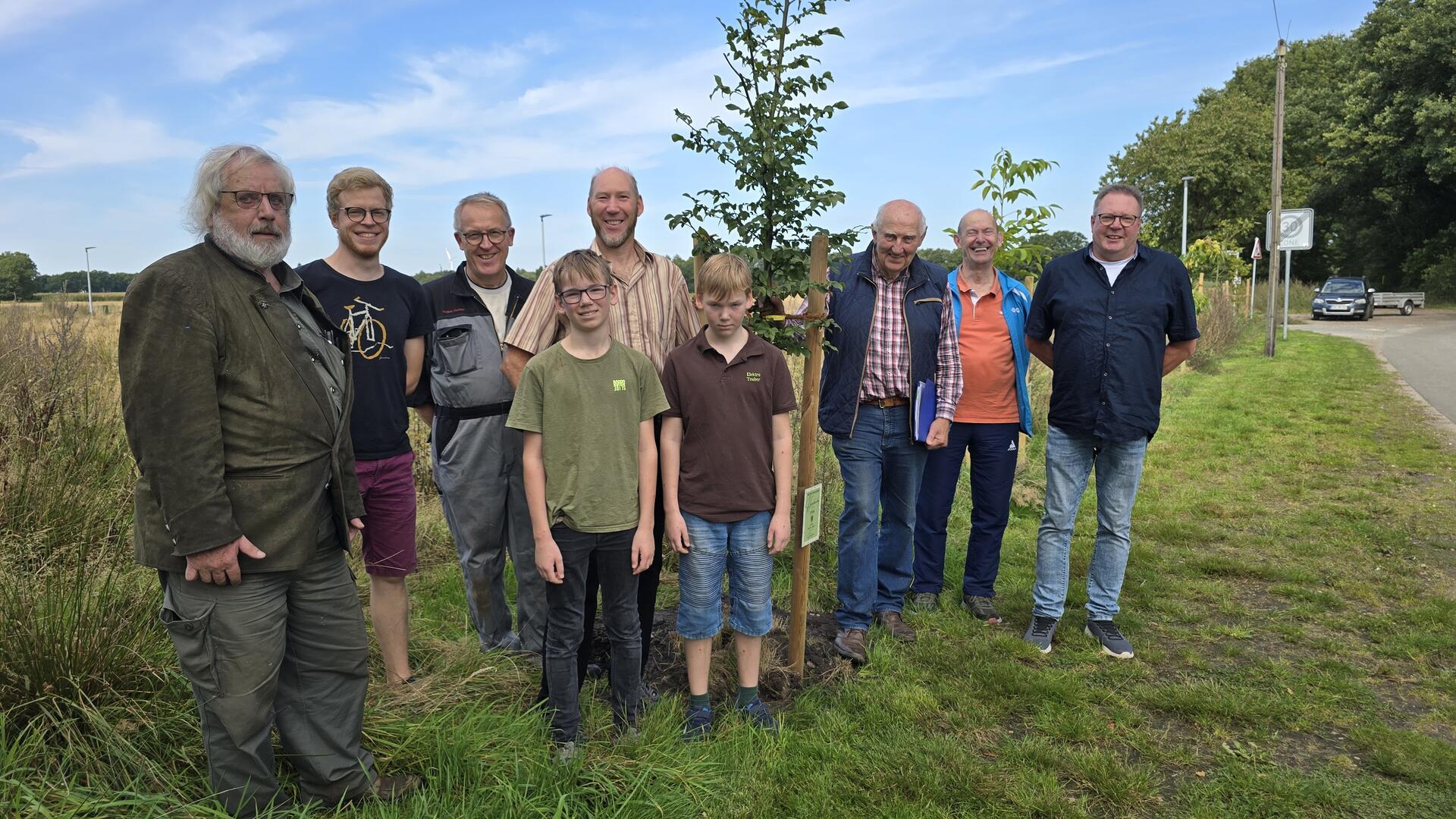 Gruppenbild mit zehn Männern und Jungen an einem Baumpflanzstreifen