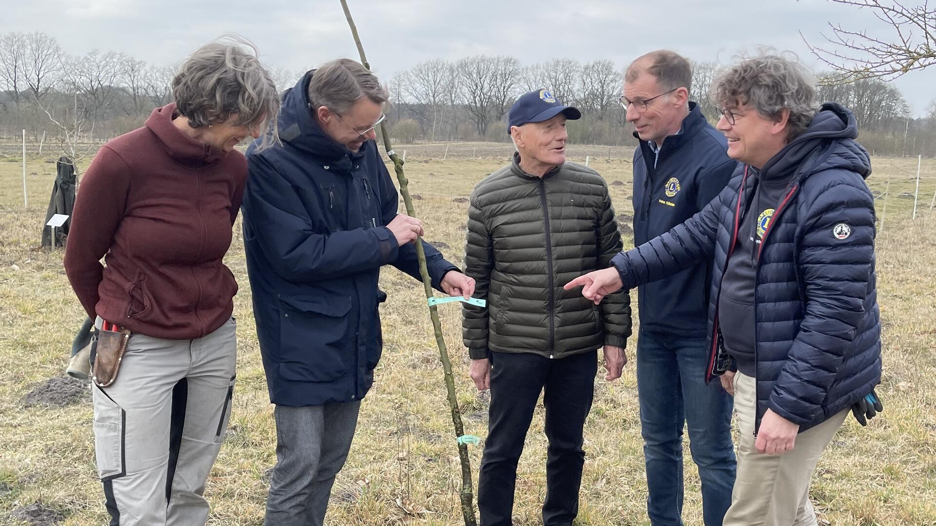 Am Rande einer Streuobstwiese werden Obstbäume gepflanzt. Dahinter steht eine Aktion des Zevener Lions Club.