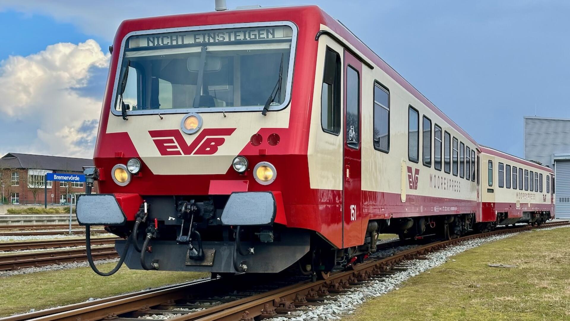 Ein rot-beige lackierter Zug steht auf dem Gleis