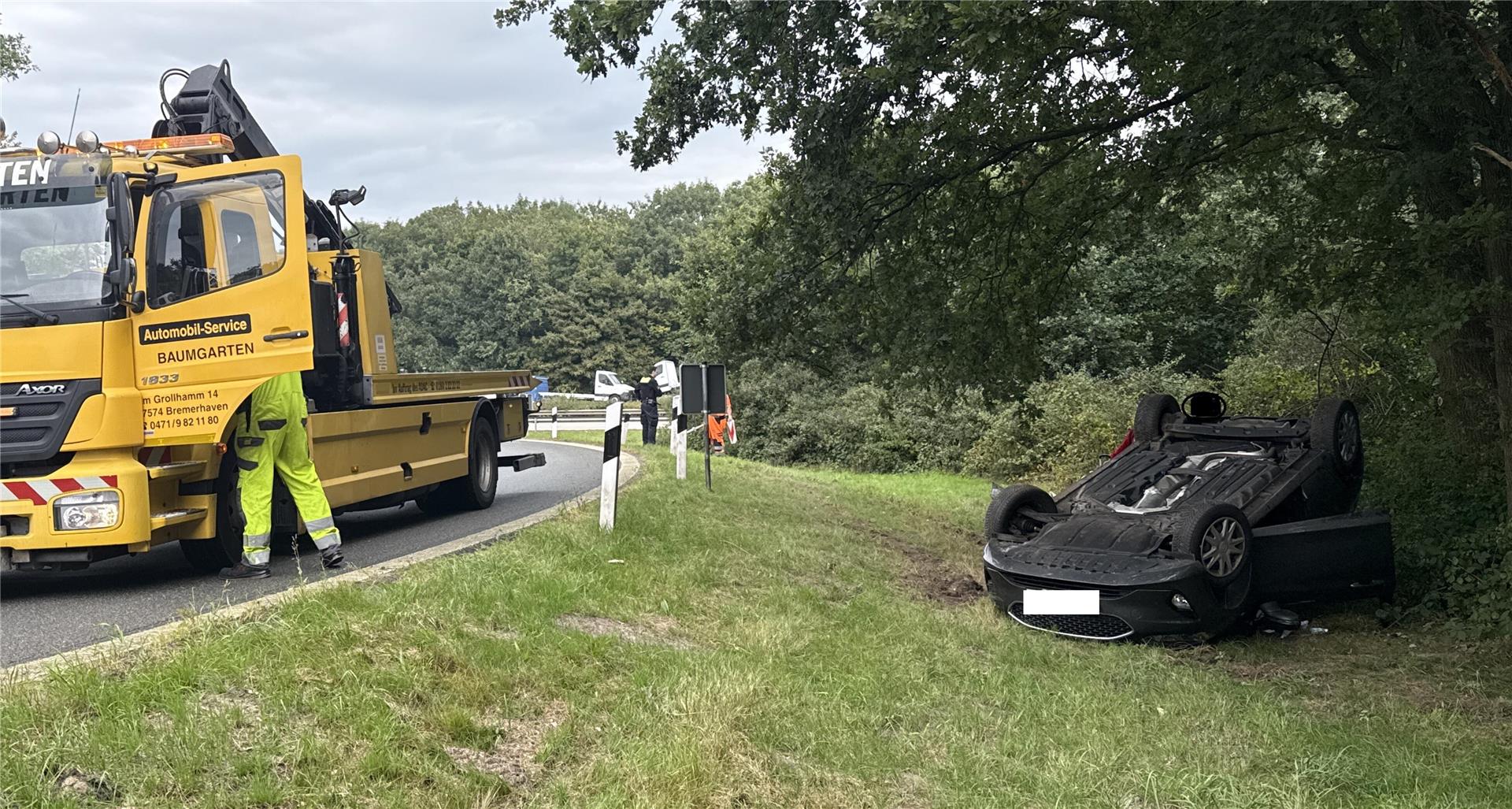 Ein verunglücktes Auto liegt in einer Autobahnabfahrt auf dem Dach.