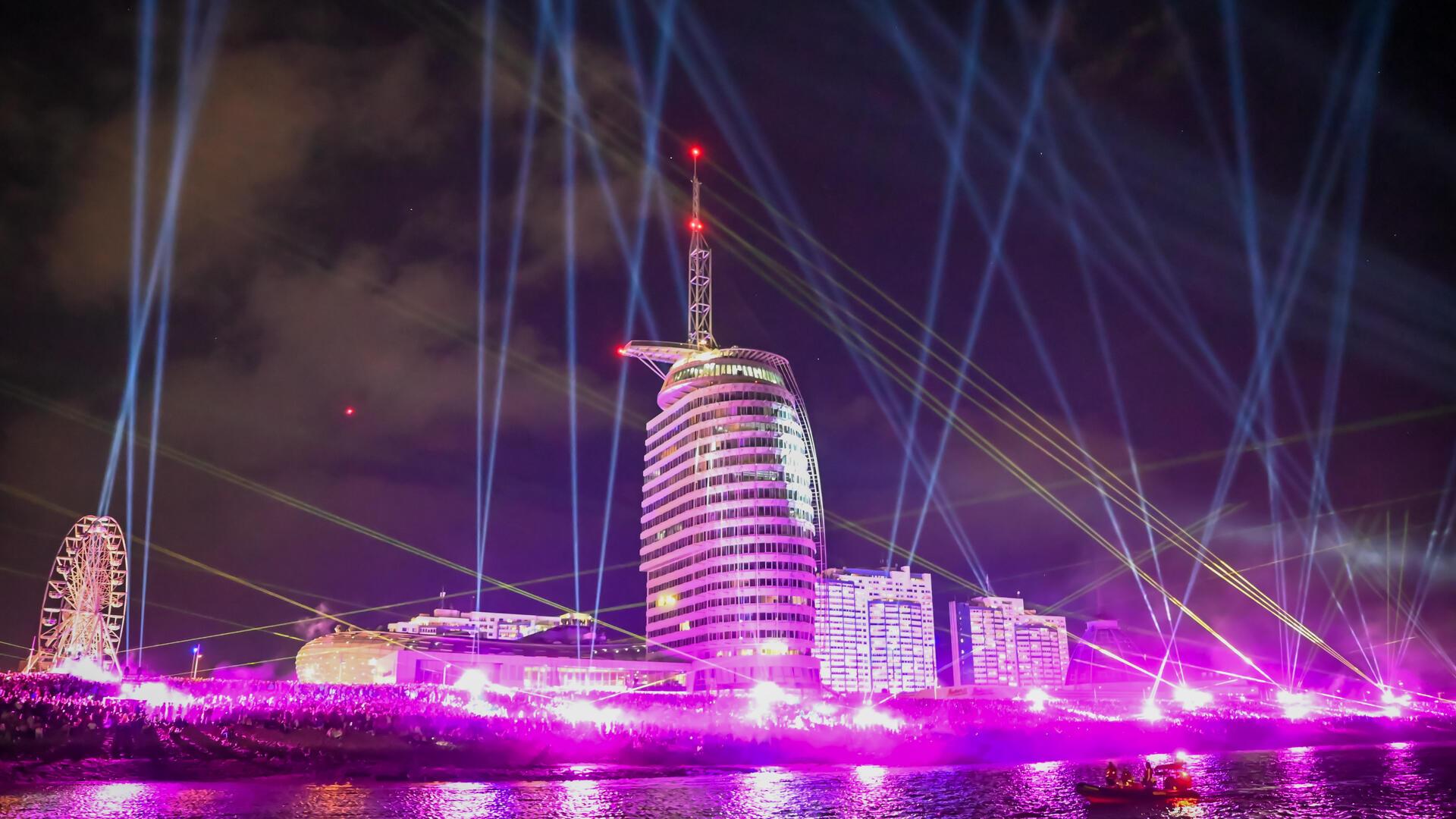 Der Deich in Bremerhaven ist während der Sail 2025 in pinkes Licht gehüllt.