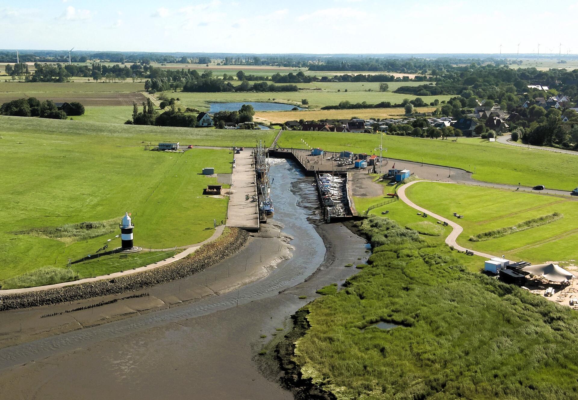Der Wremer Sielhafen von der Seeseite aus betrachtet. Das Sielbauwerk befindet sich im Seedeich hinter dem Hafen. Dahinter liegt der Mahlbusen (Teich), der zum Spülen des Hafens angelegt wurde.