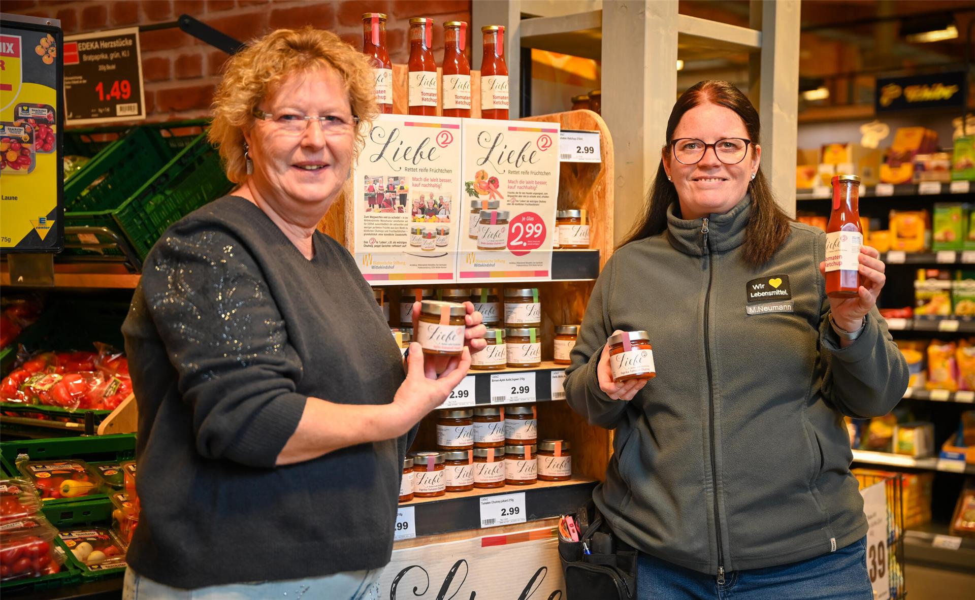 Zwei Frauen, die Gläser mit Chutney-Füllung präsentieren. Hinter ihnen steht ein Verkaufsregal.
