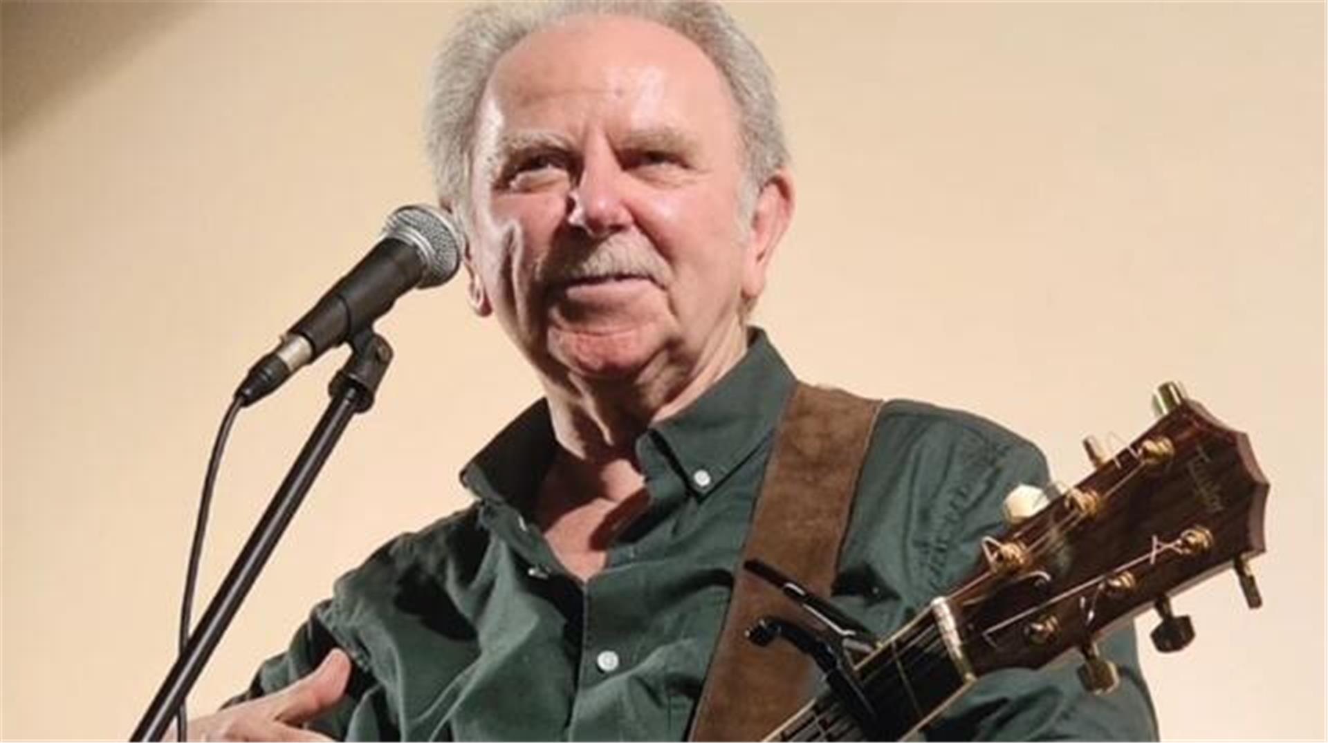 Ein Mann mit Gitarre am Mikrofon.