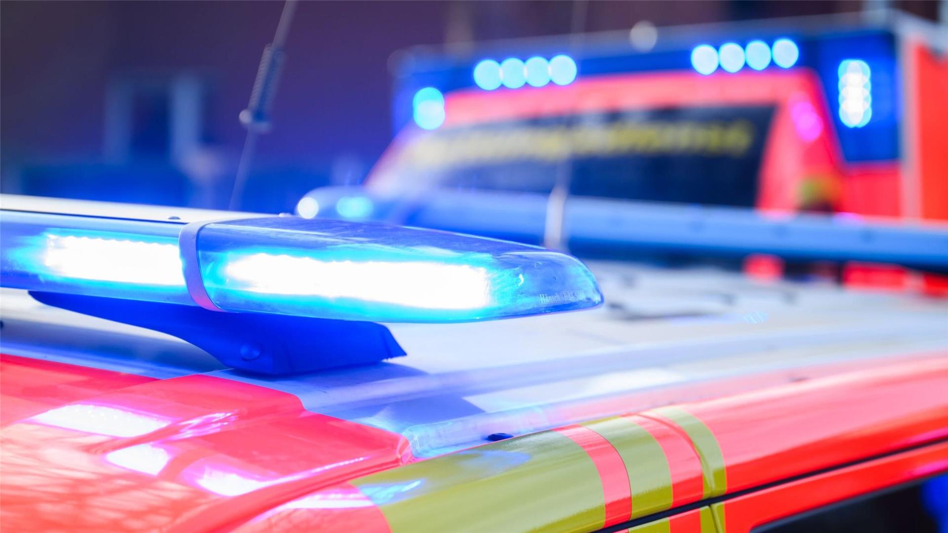 Blaulichter leuchten an einer Einsatzstelle auf einem Notarztfahrzeug und einem Rettungswagen.