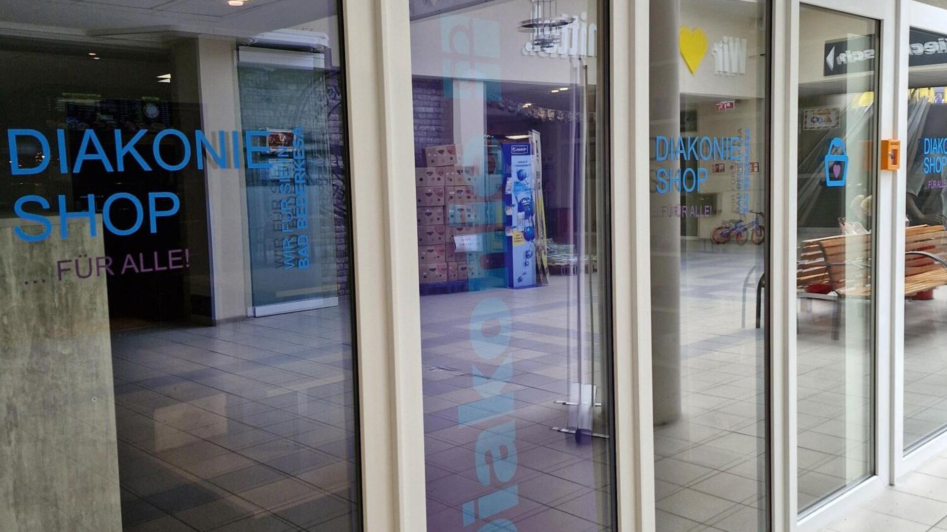Außenansicht des neuen Diakonie-Shops in der Rolandpassage in Bad Bederkesa mit Glasfassade, blauer Aufschrift „Diakonie Shop … für alle!“ und Blick ins Innere.