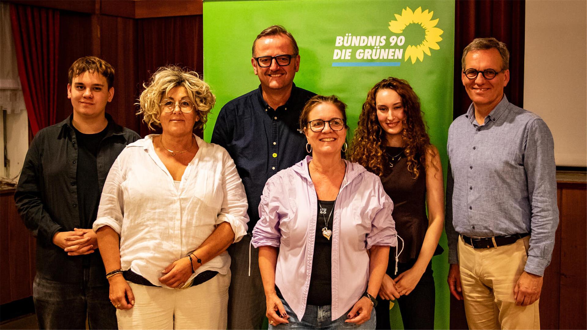 Ein Gruppenfoto mit mehreren Menschen vor einem Banner, auf dem grünen Bündnis 90/Die Grünen steht. 