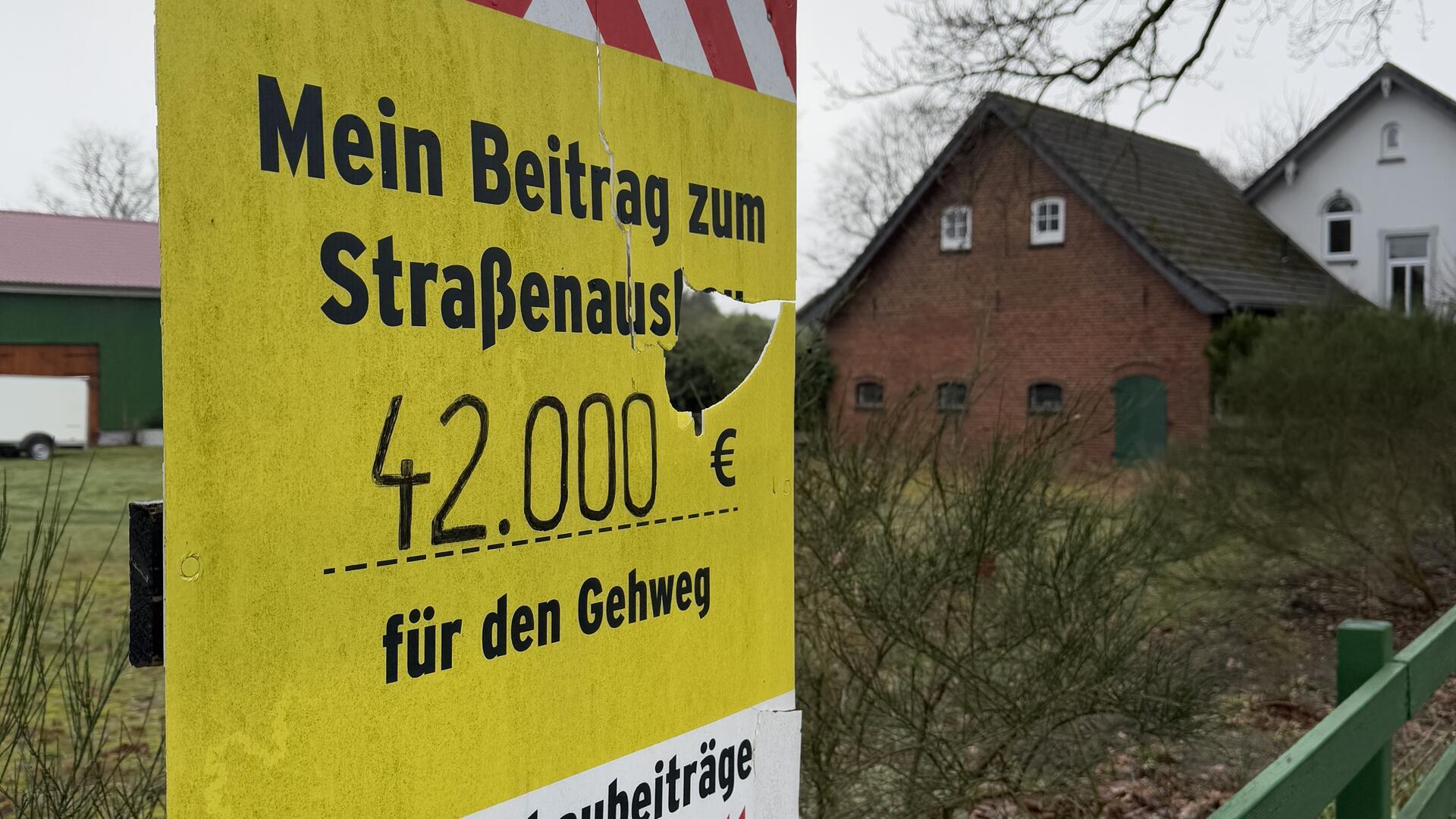 Die Anwohner der Ortsdurchfahrtsstraße stellen Schilder mit ihrem Eigenanteil an den Straßenbaukosten auf.