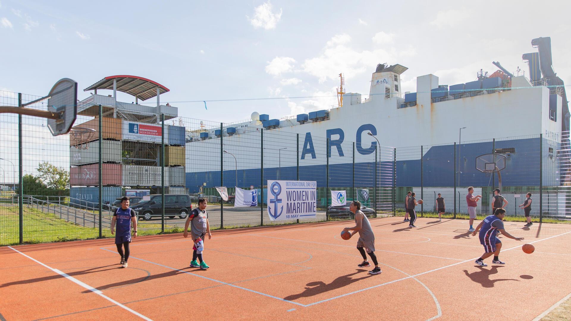 Menschen spielen auf Open-Air-Feld Basketball.