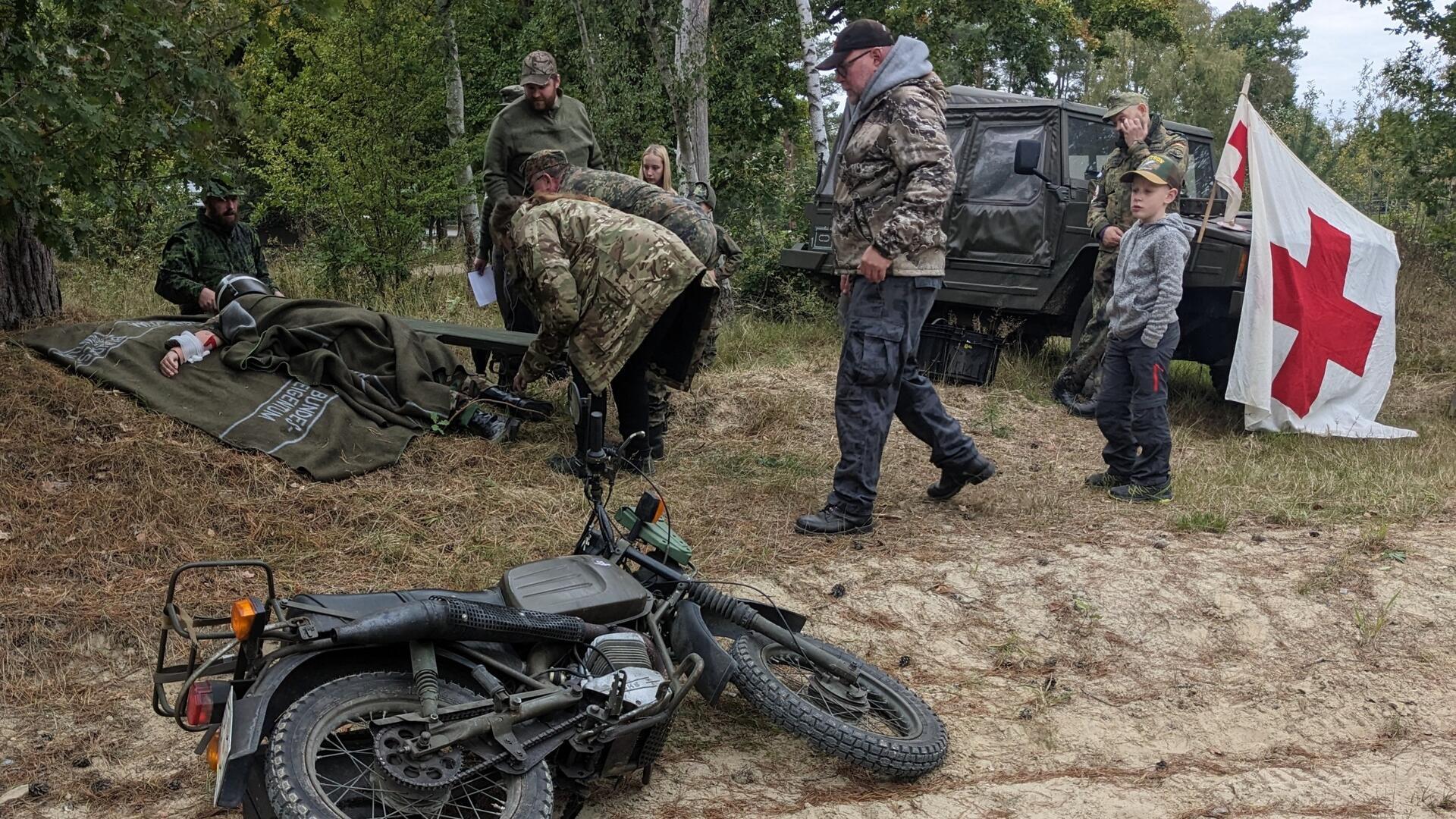 Mehrere Männer, ein liegendes Motorrad und ein Jeep