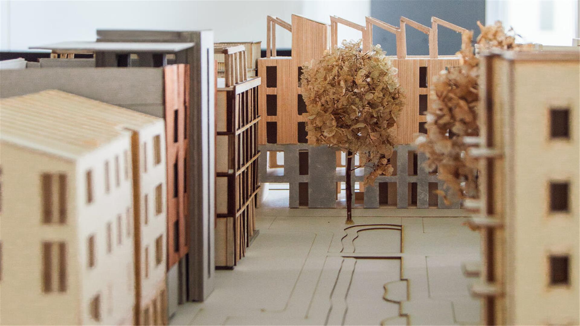 Detailaufnahme eines Architekturmodells mit Holzbauten, Innenhof und Bäumen, das nachhaltige städtische Wohnformen im Werftquartier zeigt.