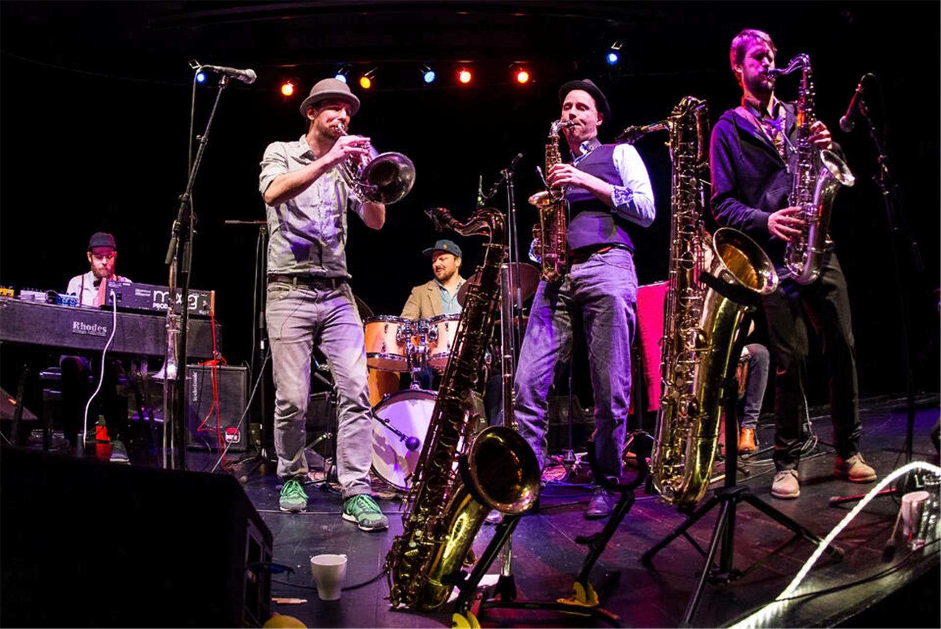 Fünf Musiker auf der Bühne mit Saxofon, Trompete, am Schlagzeug und Keyboard