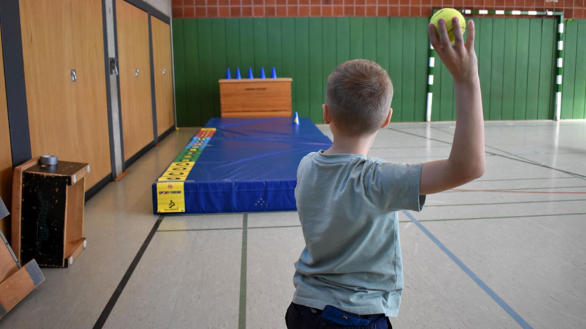 Ein Junge ist von hinten zu sehen und will mit einem Ball werfen.
