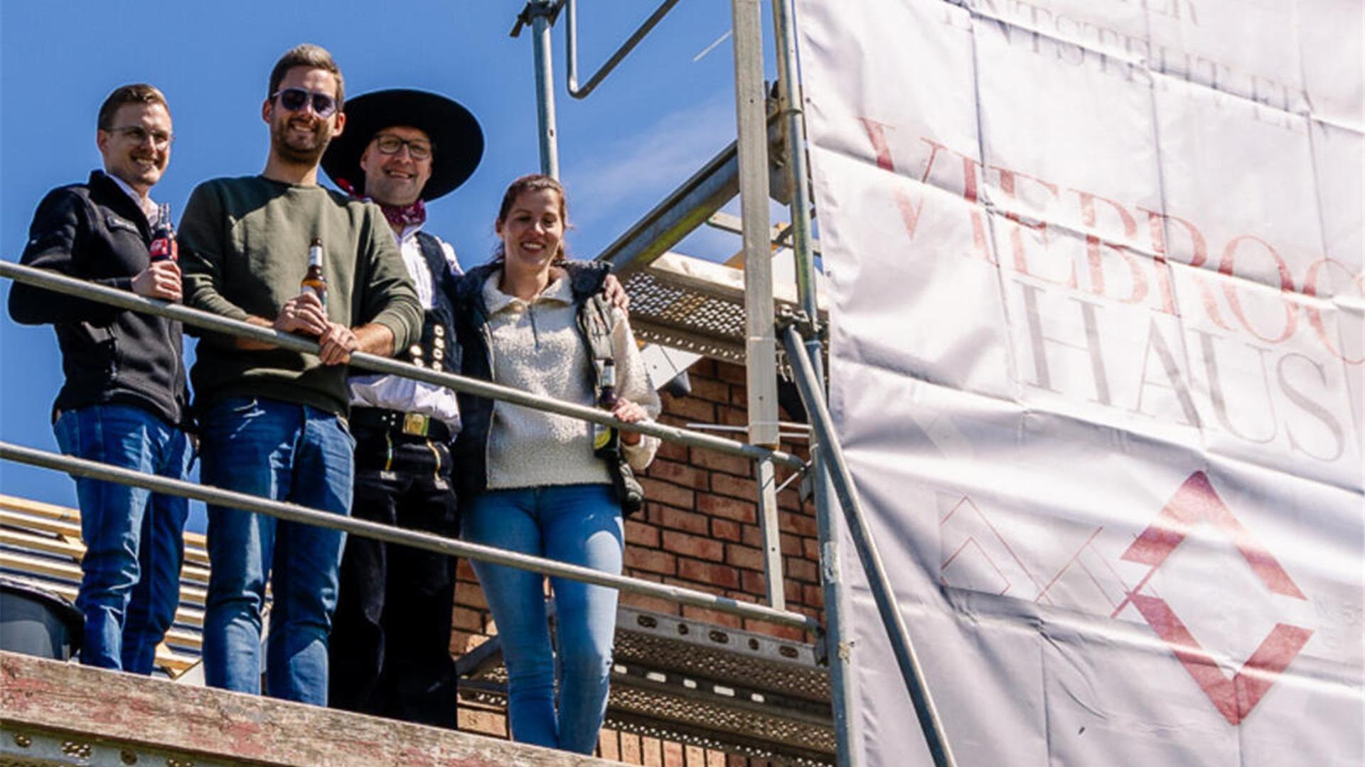 Die Bauherren in Schönberg können wieder lachen: Sie stehen beim Richtfest auf dem Gerüst rund um ihr neues Haus.