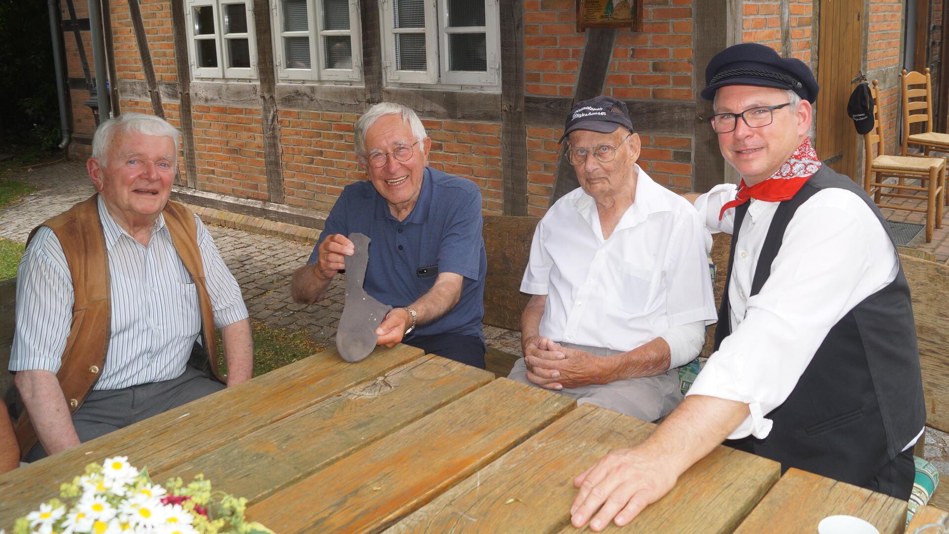 Die Brüder Peter (von links) und Bernd Klingner erklären Willi Voß, wer einst welchen Teil der Socke strickte. Oliver von Studnitz ist heute im Vorstand des Heimatvereins und freut sich über dieses Zusatzwissen zur Sammlung.