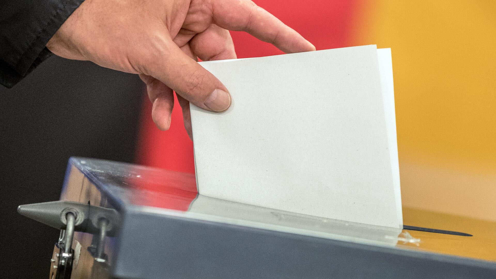 Wähler wirft seinen Stimmzettel zur Bundestagswahl in die Wahlurne