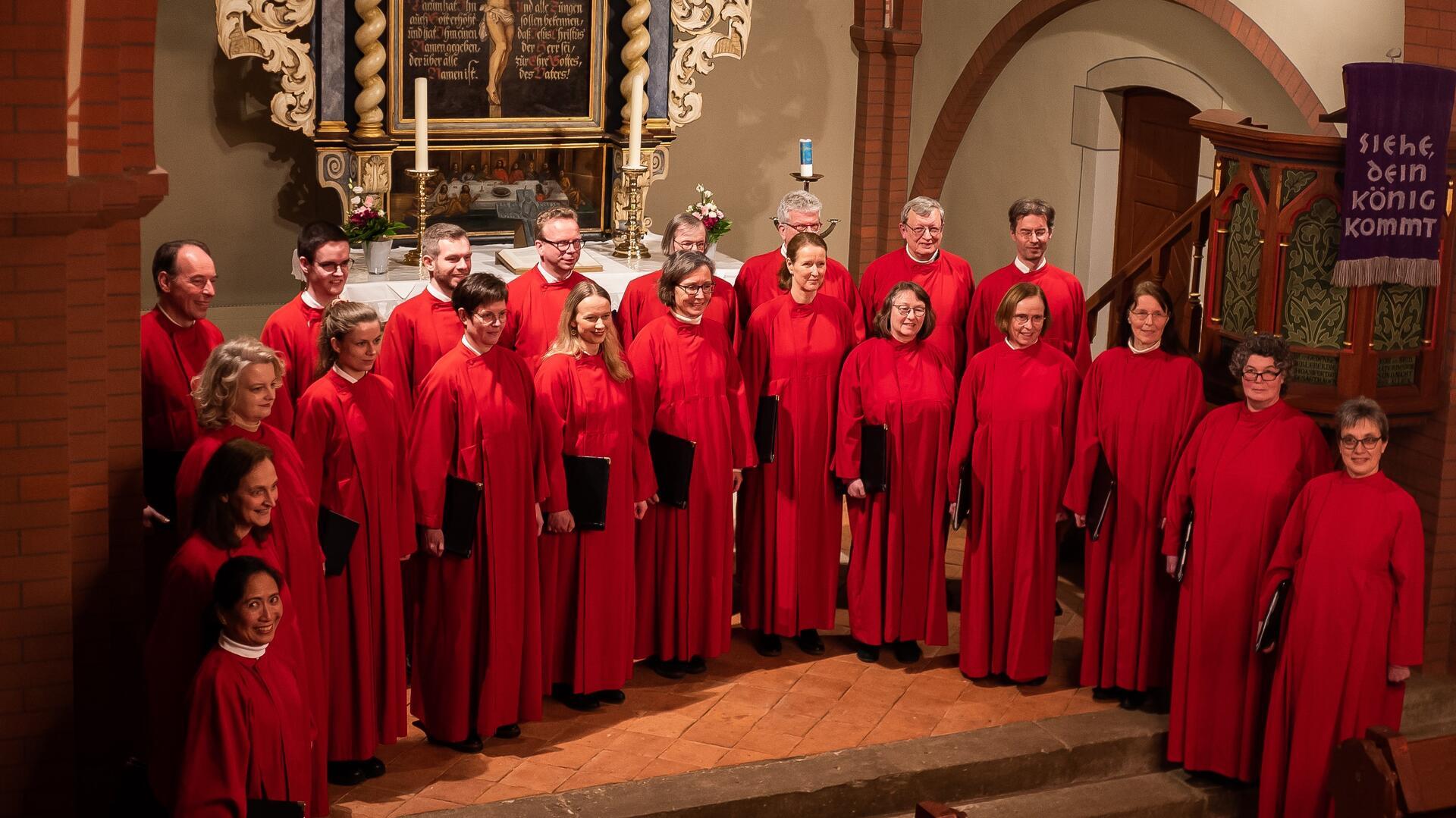 Menschen in roten Chorgewändern stehen vor einem Altar. 