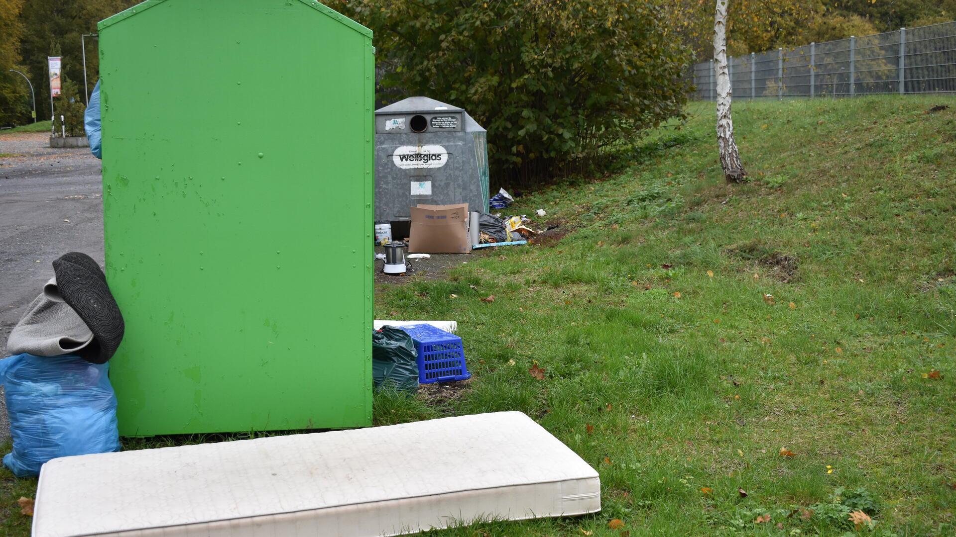 Müll liegt neben einem großen grünen Kasten.