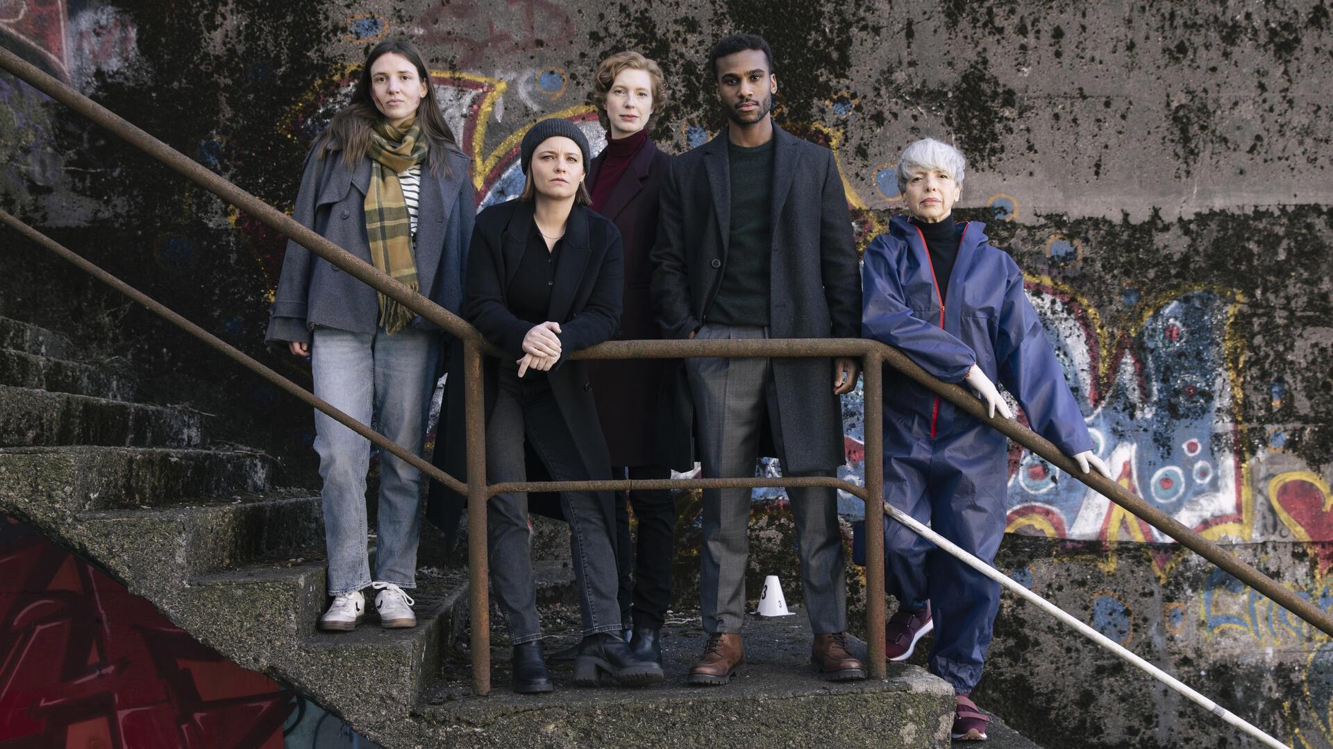 Fünf Schauspieler stehen auf einer Treppe und schauen in die Kamera. Es handelt sich um ein Foto, das bei den Dreharbeiten zu einem neuen "Tatort" entstanden ist. 