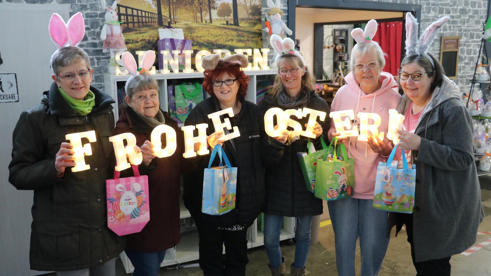Frauen mit Osterhasenohren und einem Schriftzug „Frohe Ostern“: Der Verein macht Senioren zu Ostern
