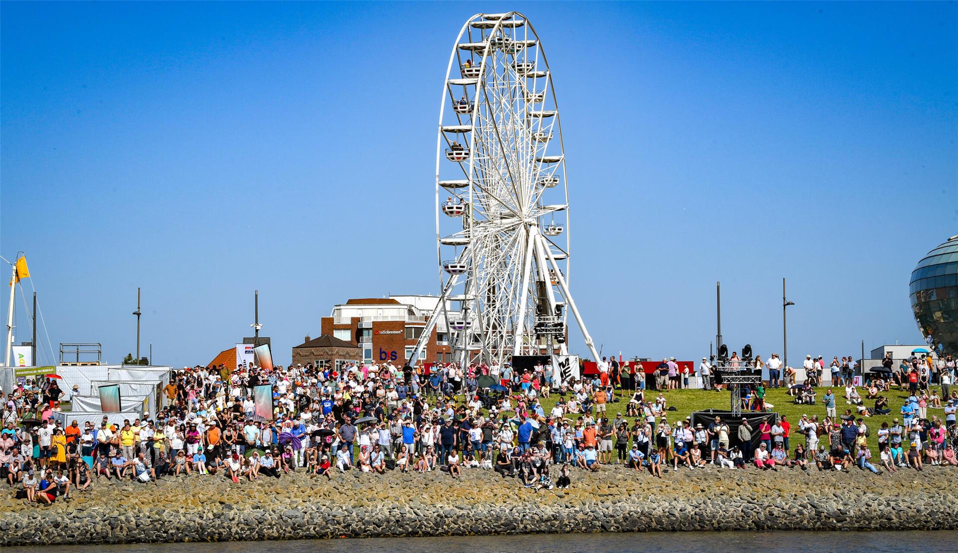 Eine Menschenmenge auf dem Weserdeich. Im Hintergrund das Riesenrad.