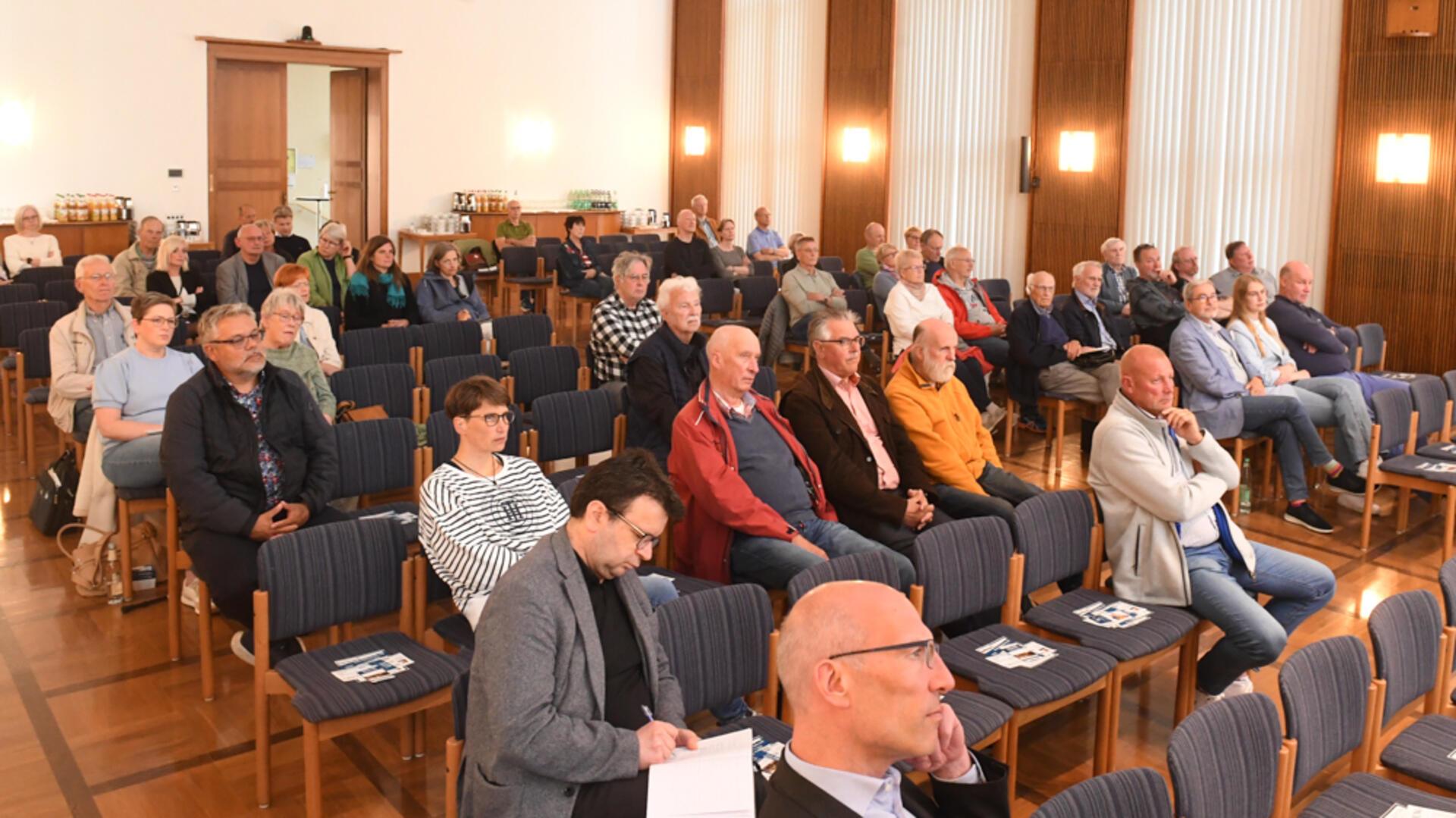 Menschen sitzen in einem Raum und hören zu.