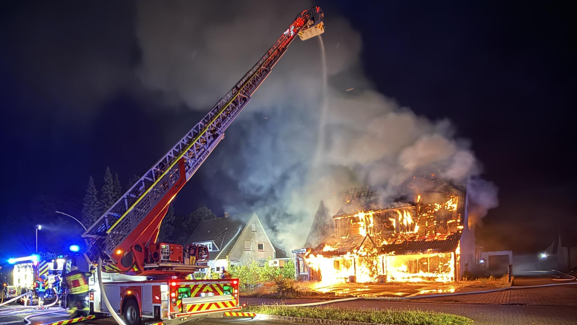 Ein brennendes Haus, das von der Feuerwehr gelöscht wird.